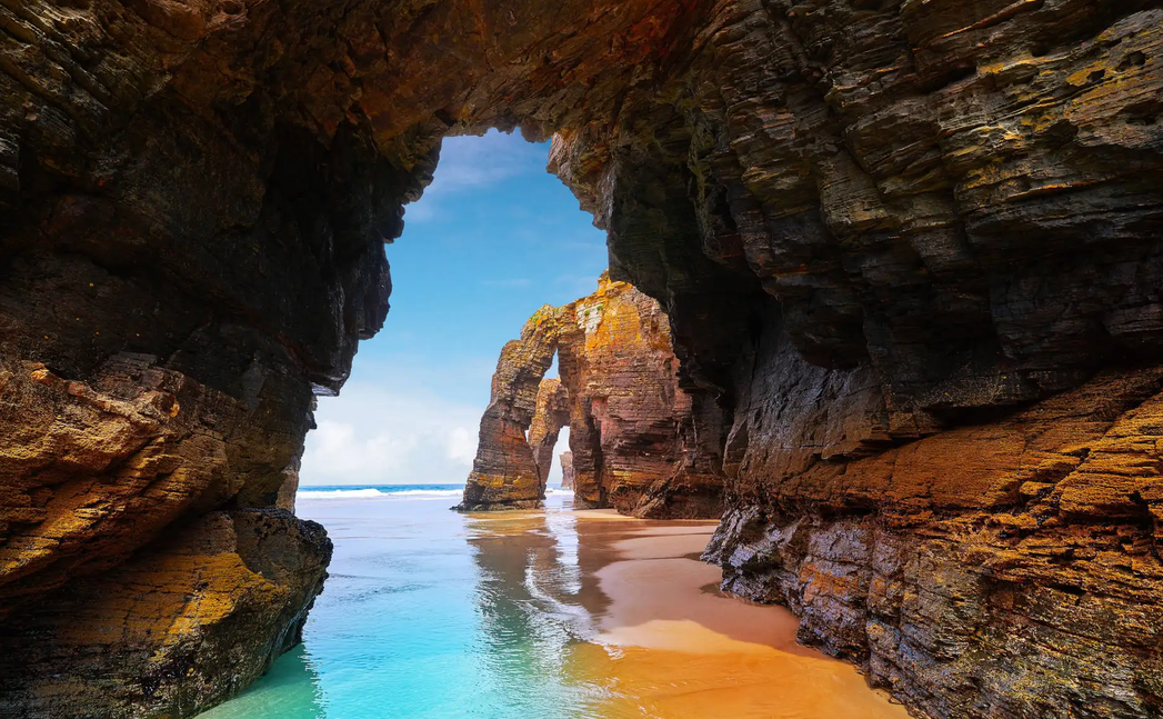 The soaring rock arches of Praia das Catedrais framing the blue Atlantic at low tide