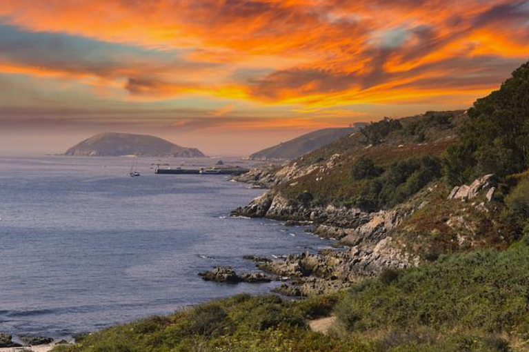 Sunset over the granite coast and pine-covered headlands of Galicia